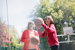 Active senior women friends playing basketball in sunny park