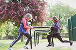 Active senior female runners stretching legs in park