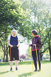 Active senior couple exercising, stretching with resistance bands in sunny park
