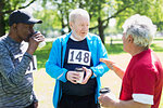Active senior men friends finishing sports race and drinking coffee in sunny park