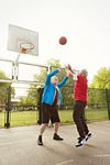 Active senior men friends playing basketball in park