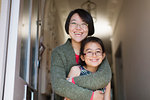 Portrait happy, affectionate mother and daughter hugging in doorway