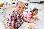 Portrait smiling grandfather eating noodles with granddaughter at table