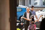 Girl running to greet grandfather and father in sunny front yard