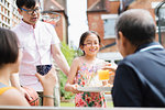 Granddaughter serving orange juice to grandfather in backyard