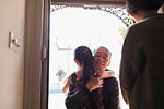 Affectionate granddaughter greeting and hugging grandfather in doorway