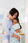 Affectionate mother and daughter hugging in bathroom