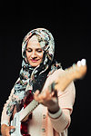Woman in floral hijab playing electric guitar