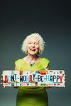 Portrait happy senior woman holding  Dont Worry Be Happy  license plates