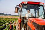 Portrait of Japanese farmer driving red tractor.