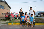 Portrait of Japanese farmer, his wife and four children standing in their yard.