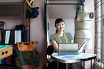 Japanese female fashion designer working in her studio, smiling at camera.