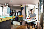 Japanese female fashion designer sitting at desk, working in her studio.