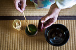 High angle close up of traditional Japanese Tea Ceremony, woman spooning green Matcha tea powder into bowl.