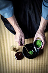 High angle close up of traditional Japanese Tea Ceremony, man spooning green Matcha tea powder into bowl.