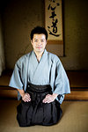 Japanese man wearing kimono sitting on floor in traditional Japanese house, looking at camera.