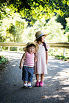 Two Japanese girls wearing sun hats standing on path, holding hands.