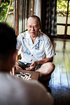 Two Japanese men sitting on floor on porch of traditional Japanese house, playing Go.