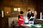 Japanese man and woman, craftspeople making Washi paper in a traditional workshop.