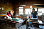 Two people, man and woman making traditional Washi paper. Trays of pulp and wooden frames and drying racks.