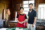Japanese woman and man standing in a Washi workshop by a vat of pulp, basic plant based ingredients for making paper.