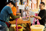 Japanese woman and man standing in a textile plant dye workshop, wringing out piece of pink fabric.