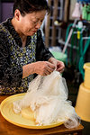 Japanese woman standing in a textile plant dye workshop, holding piece of sheer white fabric.