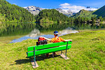 Hiker with rucksack relaxes on a bench, Lake Cavloc, Forno Valley, Maloja Pass, Engadine, Graubunden, Switzerland, Europe