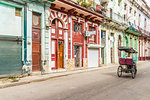 A vintage cycle rickshaw passing beautiful local architecture in Havana, Cuba, West Indies, Caribbean, Central America