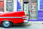 A red vintage car parked against colourful local architecture in Havana, Cuba, West Indies, Caribbean, Central America