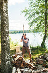 Mid adult man chopping logs in Svadsjo, Sweden