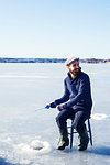 Man fishing on frozen lake in Dalarna, Sweden