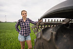 Agricultural worker standing next to a tractor in field