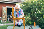 Senior man repairing a chair outdoors in Kvarnstugan, Sweden