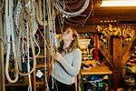 Teenage girl reaching up to touch ropes in rope maker store