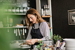 Barista holding smart phone at cafe counter