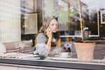 Barista using smart phone behind cafe window