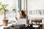 Barista using smart phone by laptop in cafe