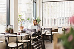 Barista using smart phone by laptop in cafe