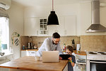 Mid adult man and a boy looking at a tablet in a domestic kitchen in Sweden