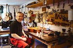 Craftsman smiling in guitar making workshop
