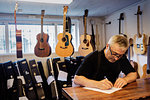 Craftsman writing in guitar making workshop