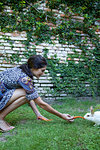 Woman feeding carrots to a rabbit