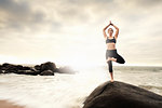Woman practicing yoga on rocks on beach