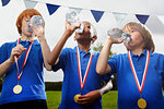 School boys with medals drinking water after sports event