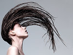 Young woman throwing wet hair back against grey background