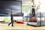 Mature foreman directing businessman carrying large pen on oversized desk