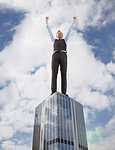 Oversized businessman cheering on skyscraper, low angle view