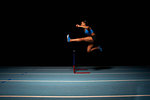 Young female athlete jumping hurdle