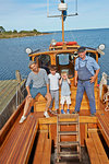 Father and two sons with fisherman on boat, Eggergrund, Sweden